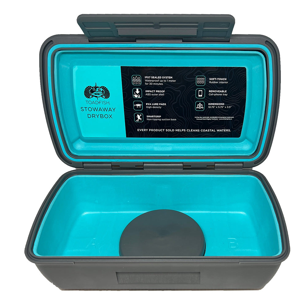 A blue and gray Toadfish Stowaway Dry Box with a smart grip and a removable cell phone tray insert, featuring a label with product information.